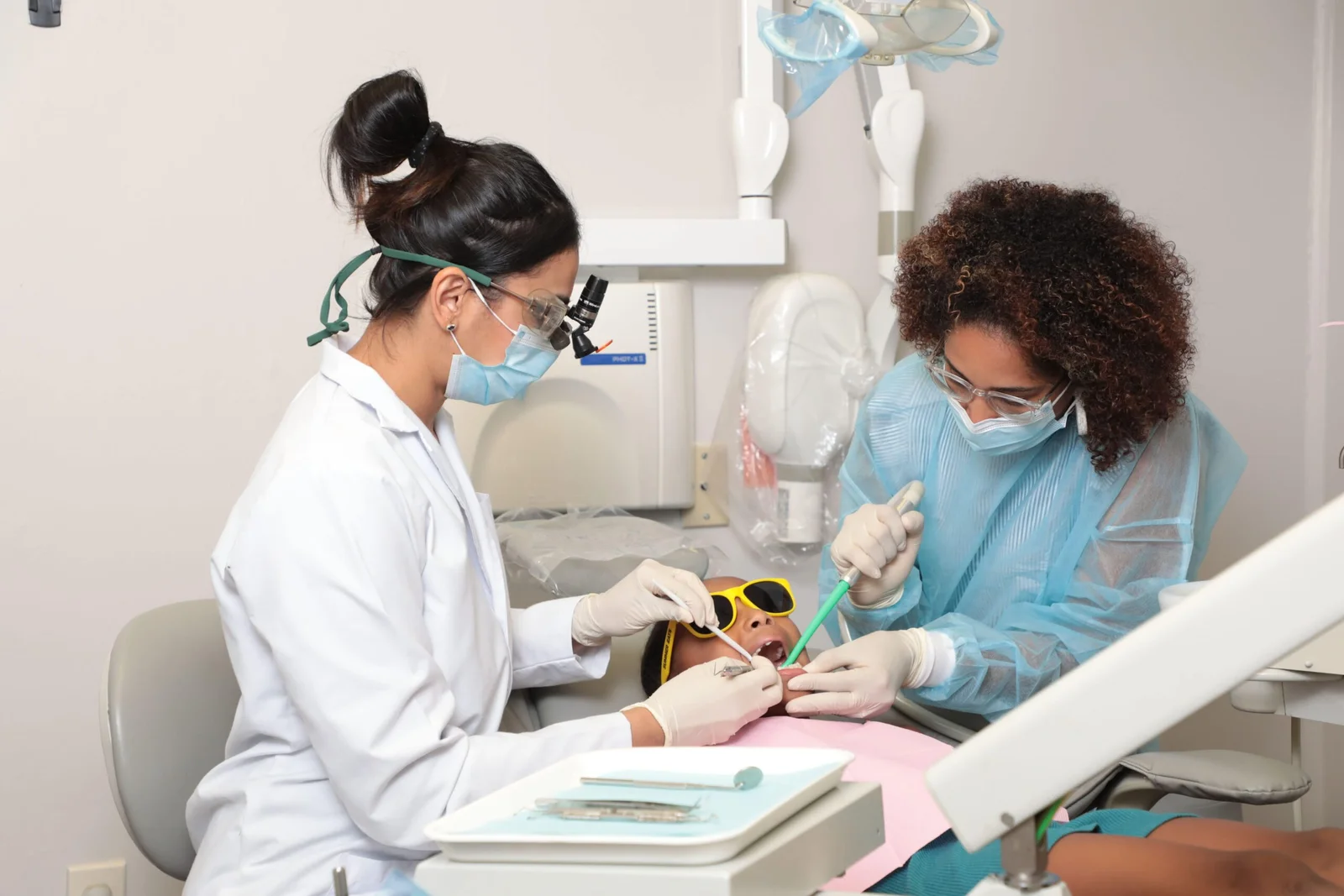 Dr. Jain and assistant performing pediatric dental treatment on a young patient
